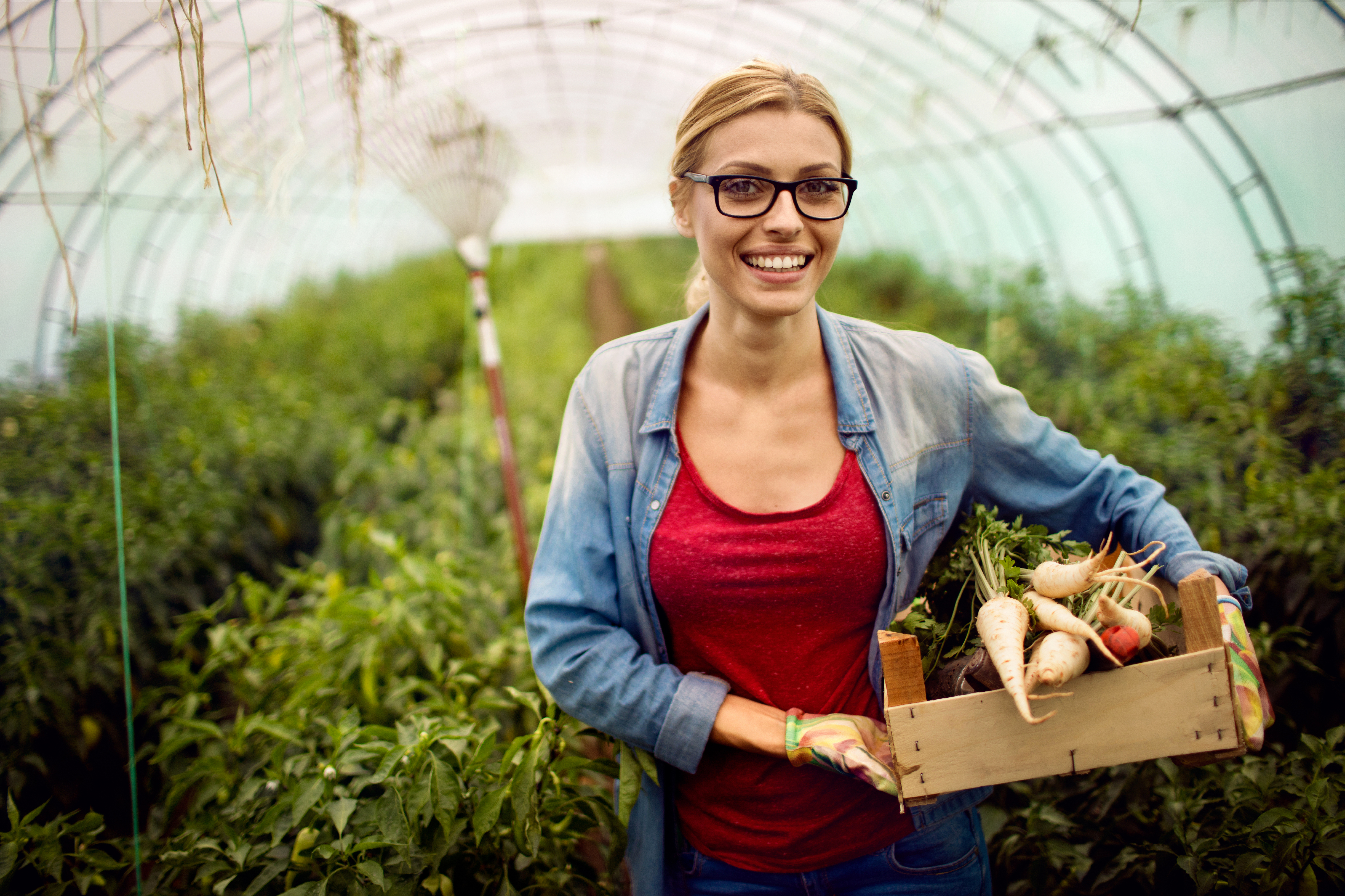 Portrait of a young smiling woman proudly showing her beet from a greenhouse