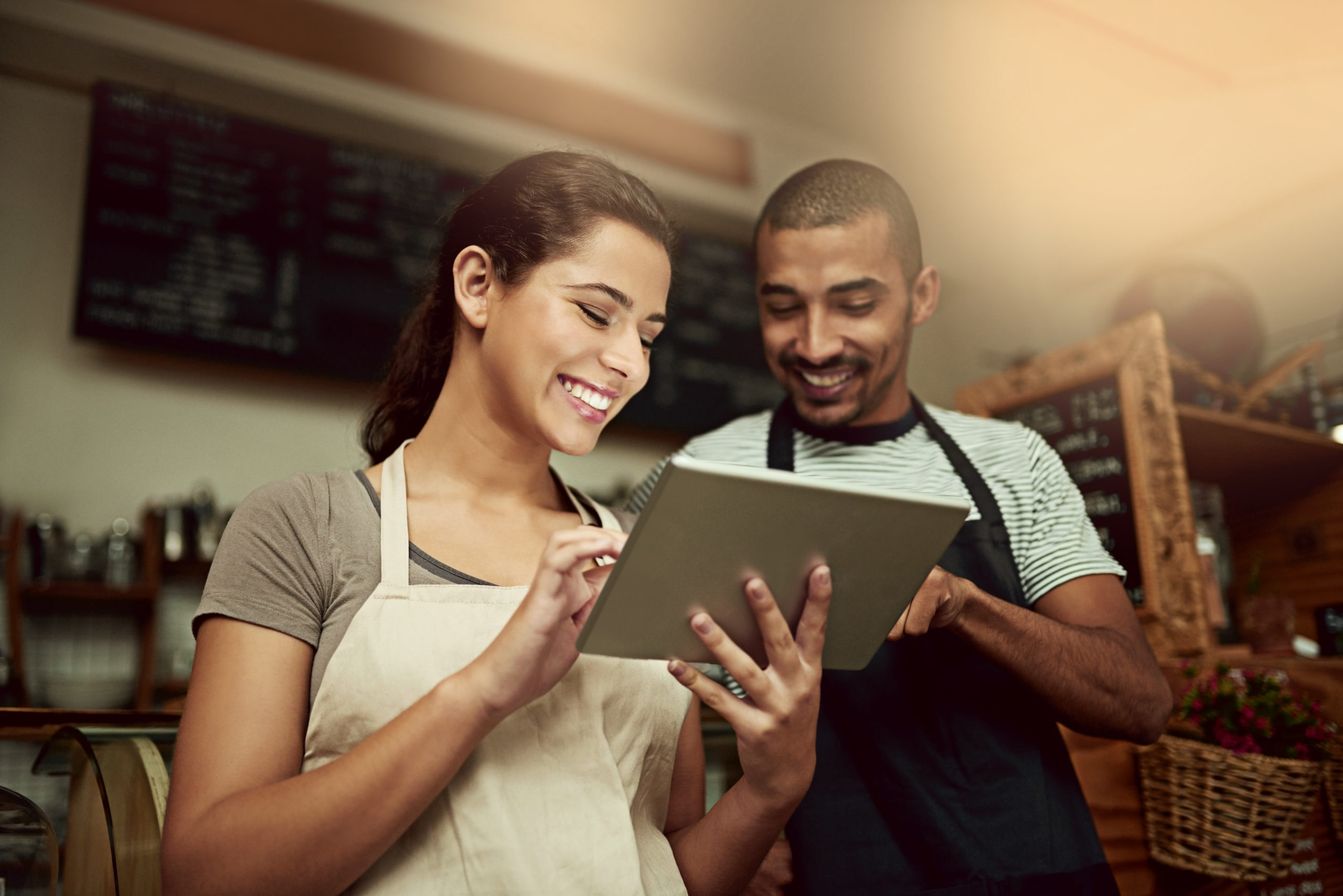Young man and woman using a digital tablet together while working in a coffee shop